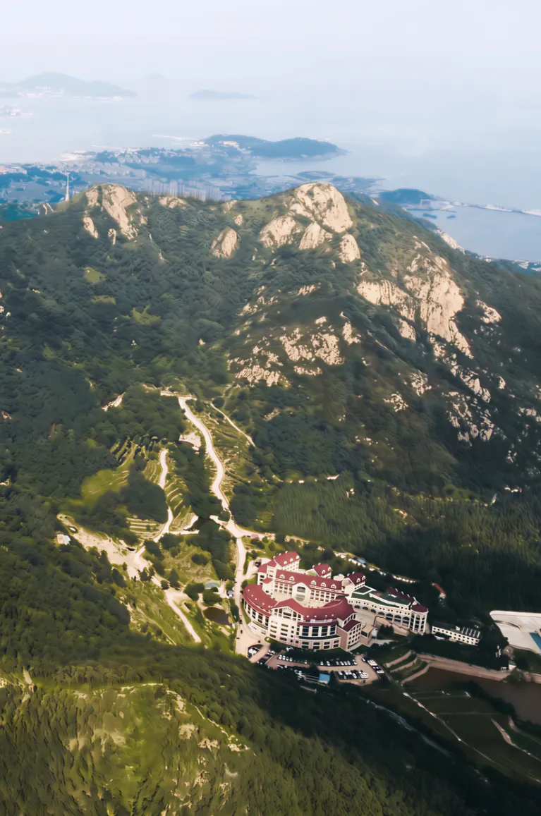 Aerial view of Qingdao United Family Hospital between mountains and the coast